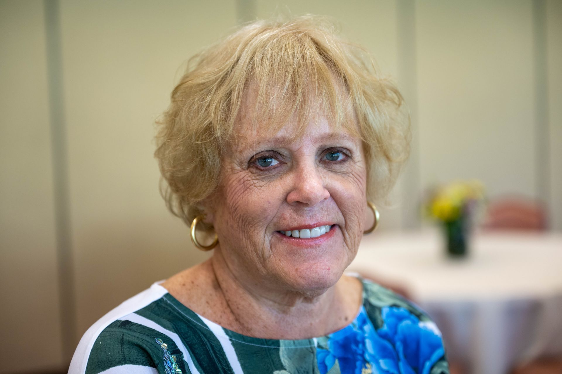 A woman in a blue and white dress is smiling for the camera.