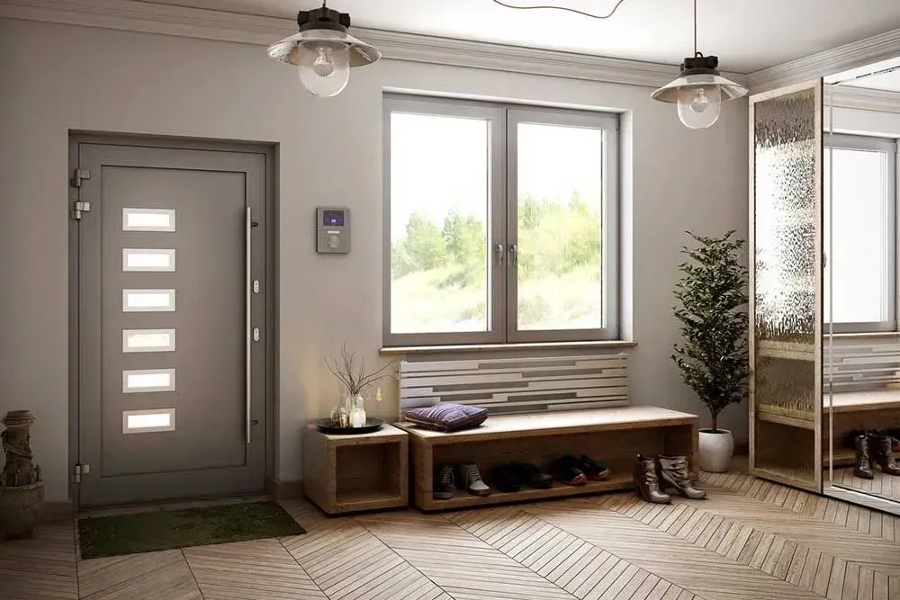 Ingresso moderno con porta grigia, panca sotto la finestra, pianta in vaso e mobile contenitore.