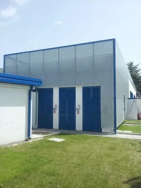 Esterno di un edificio di servizio blu e bianco con doppie porte e un prato in primo piano.