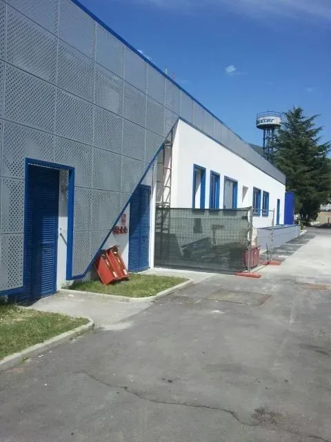 Moderno edificio industriale con porte rifinite di blu e ingresso in vetro in una giornata di sole.