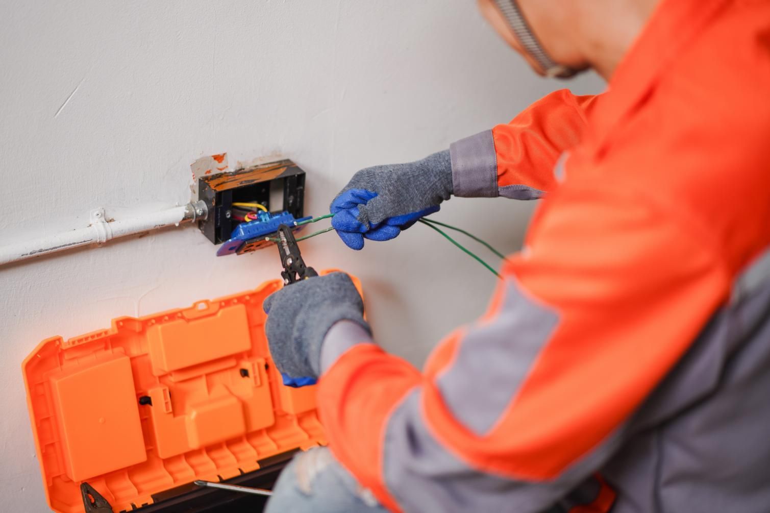Person in orange safety gear installing solar panels on a roof in sunlight.