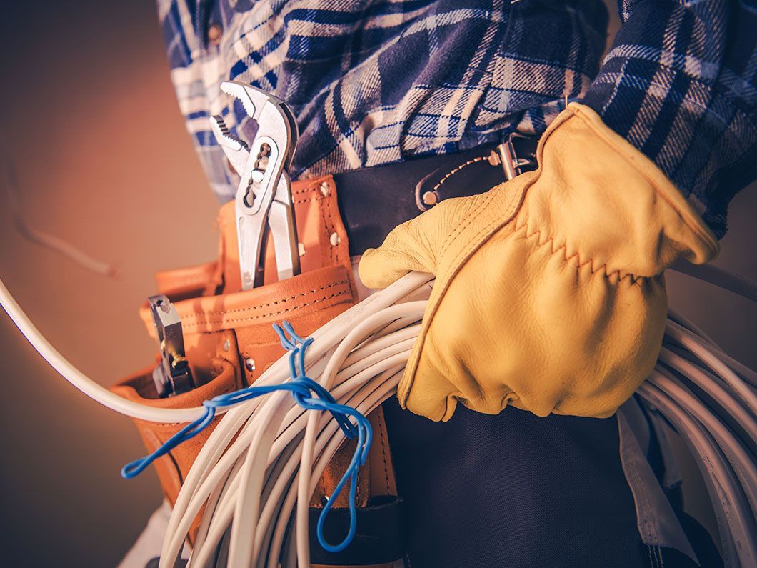 Electrician wearing work gloves and belt holding cable.