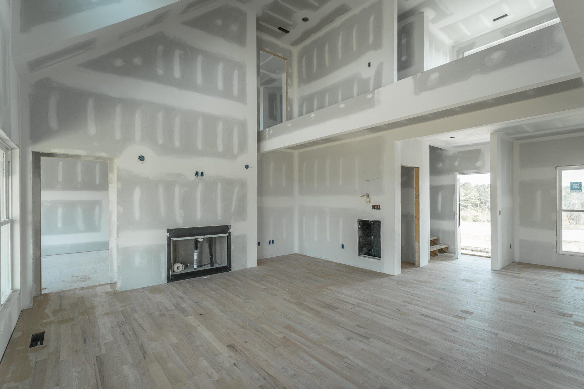 a large empty room in a house under construction with drywall on the walls .