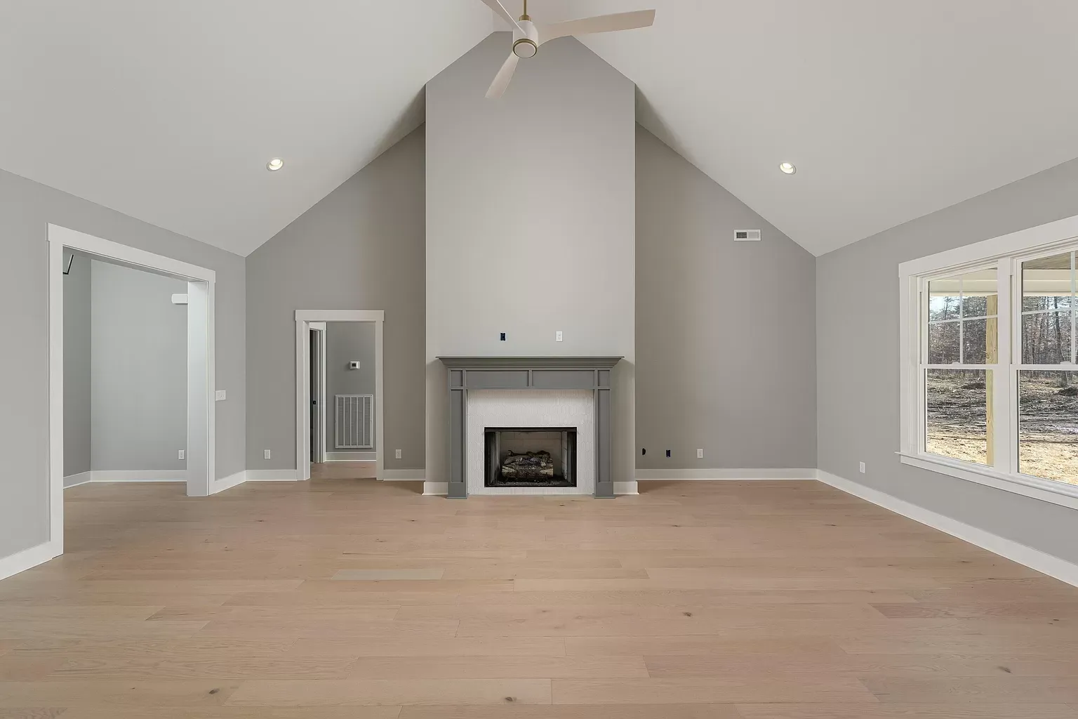an empty living room with a fireplace and vaulted ceiling