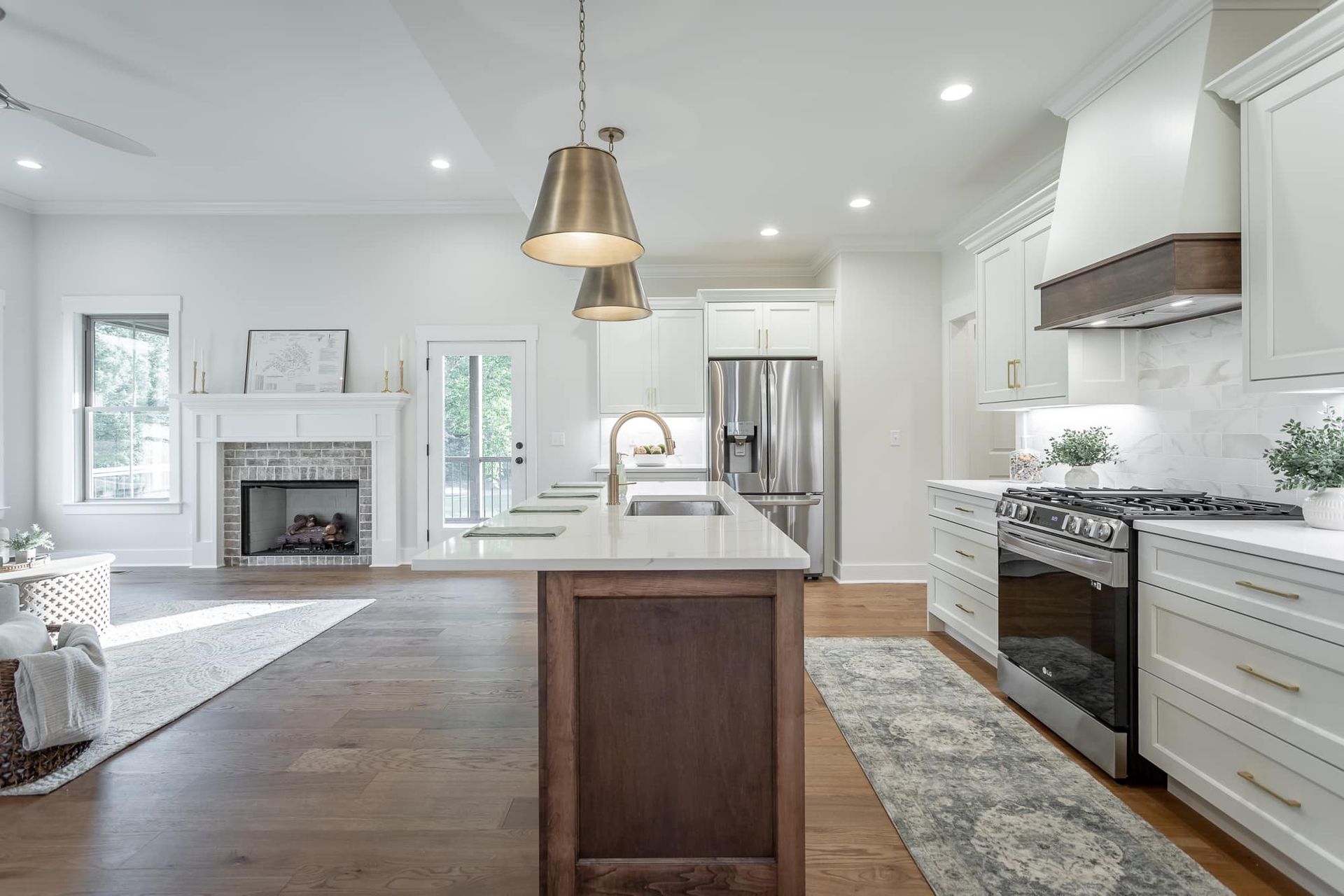 Open-concept kitchen with white cabinets, wood island, stainless steel appliances, and fireplace.