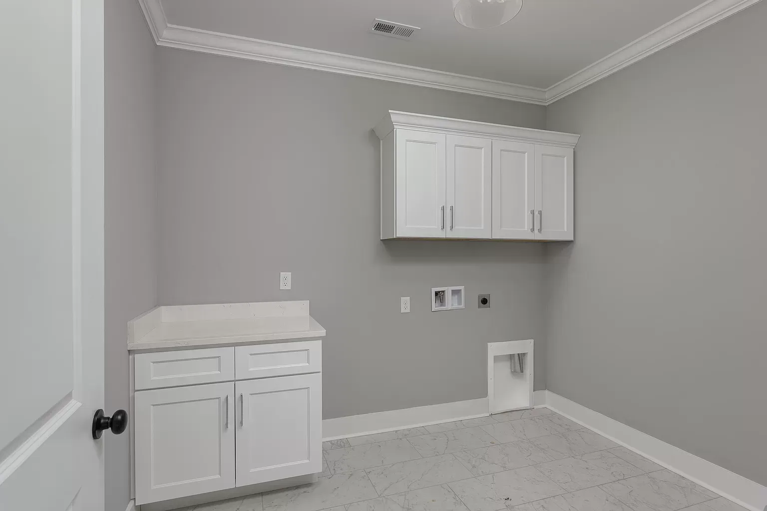 a laundry room with gray walls and white cabinets