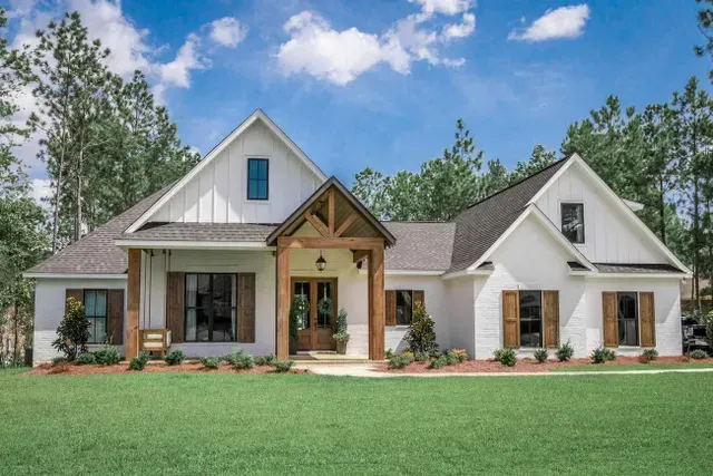 a large white house with brown shutters is sitting on top of a lush green lawn .