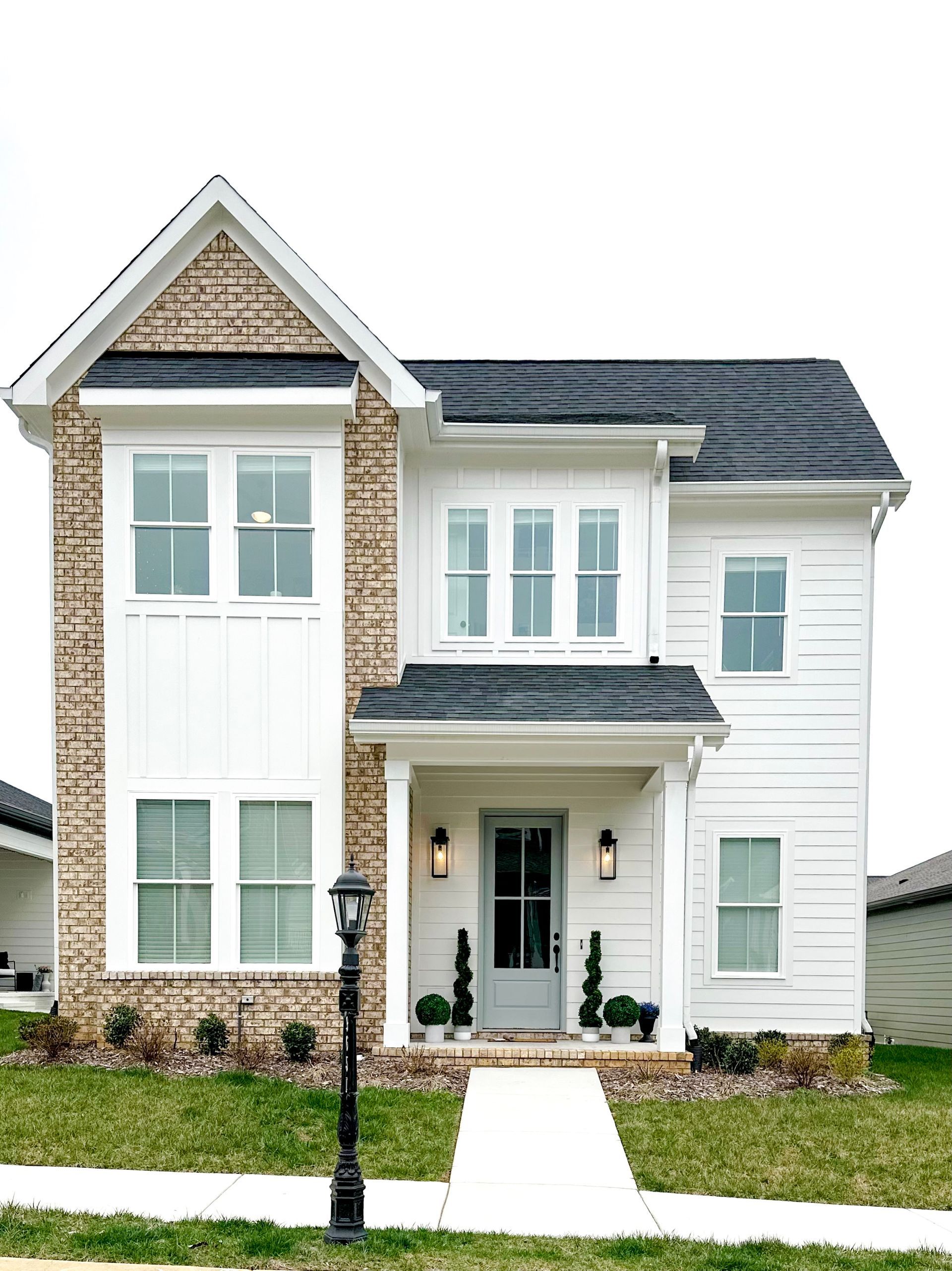 a white house with a brick facade and a black roof