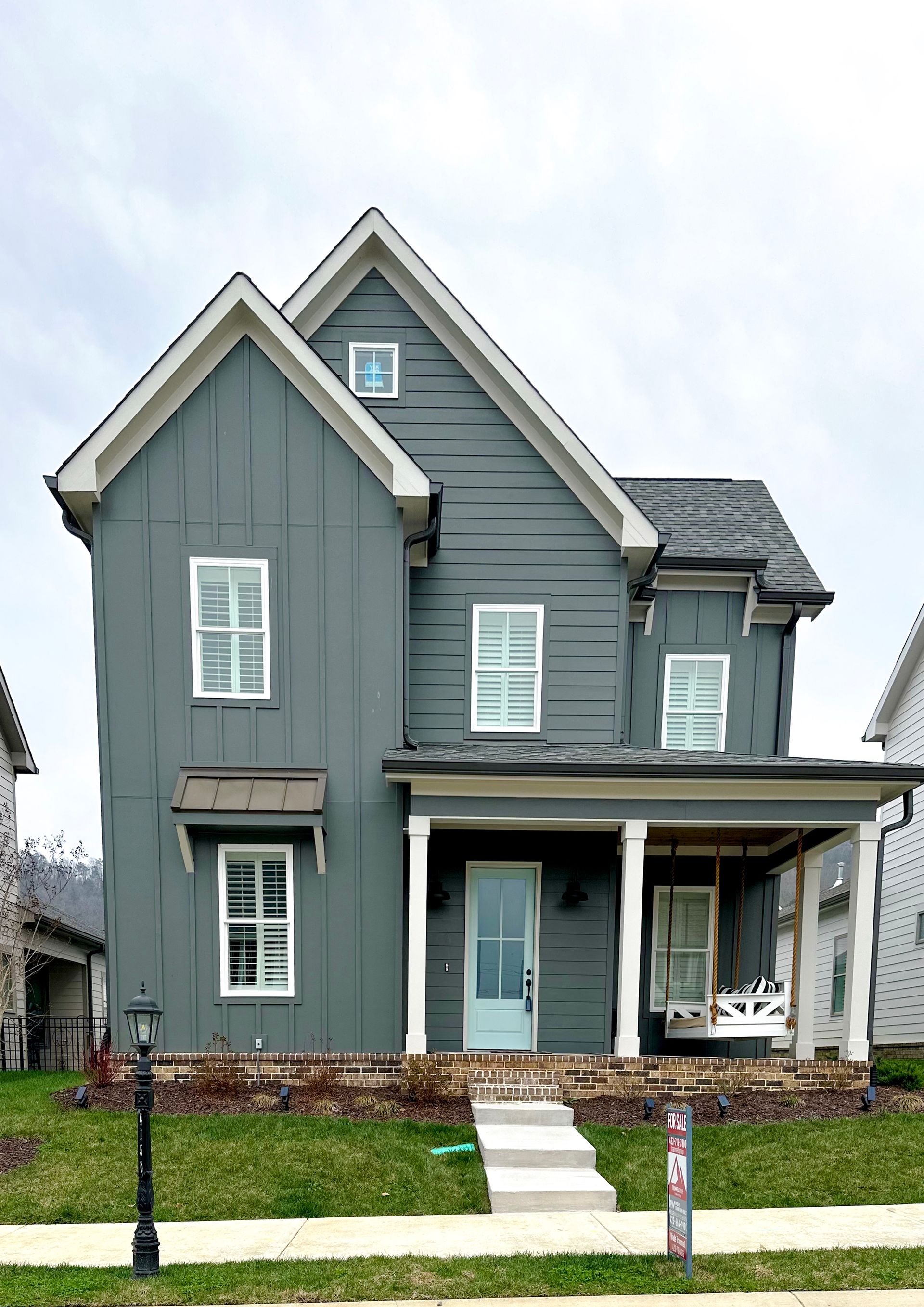 a house with a porch and a for sale sign in front of it
