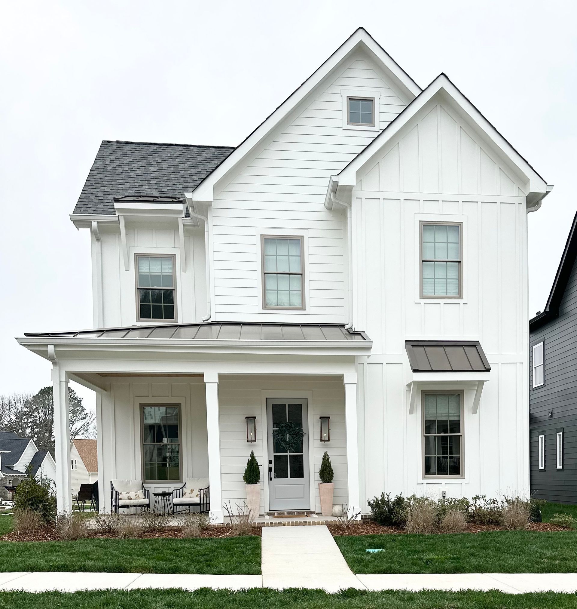 a white house with a black roof and a porch