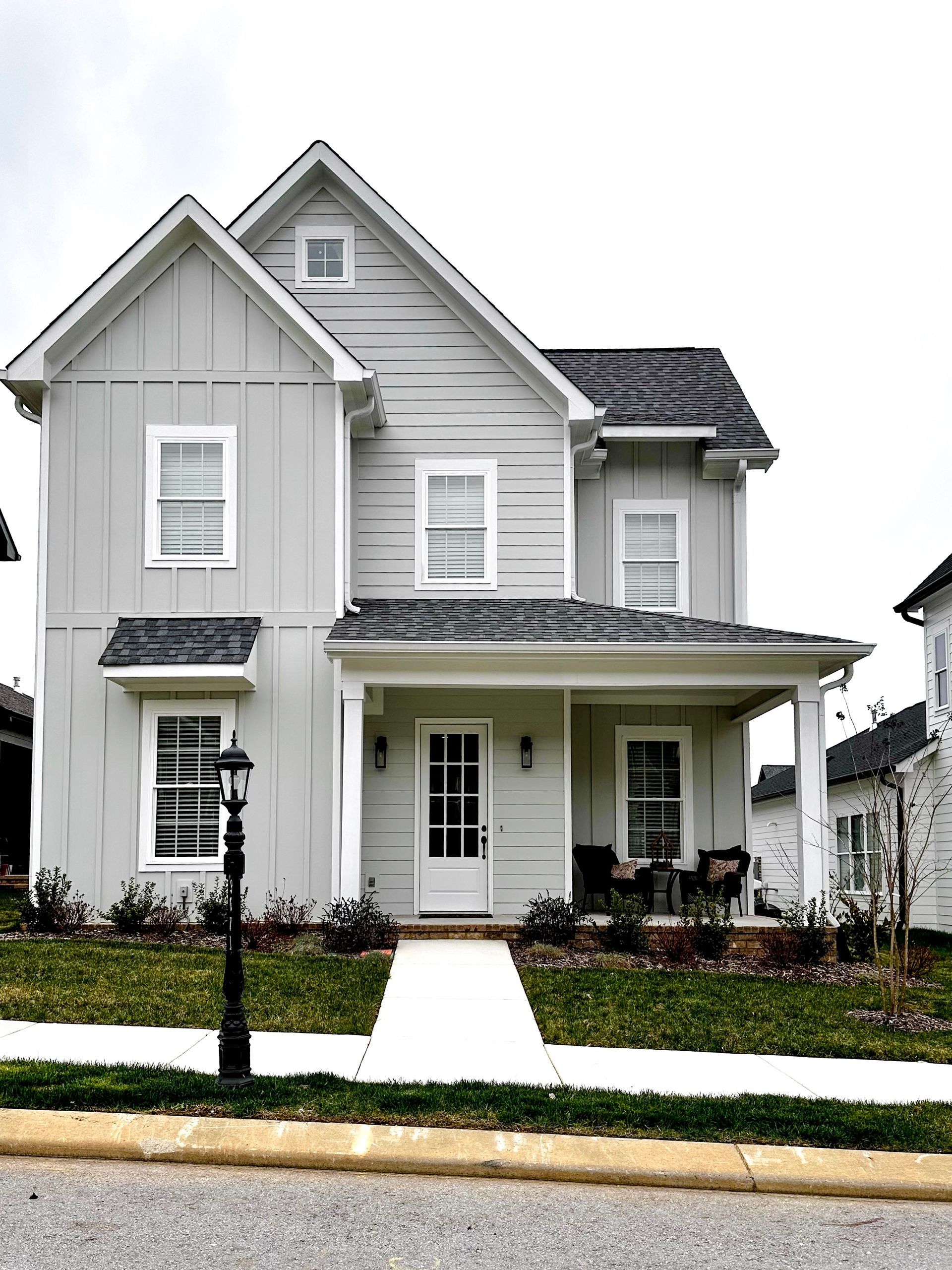 a white house with a porch and a lamp post in front of it