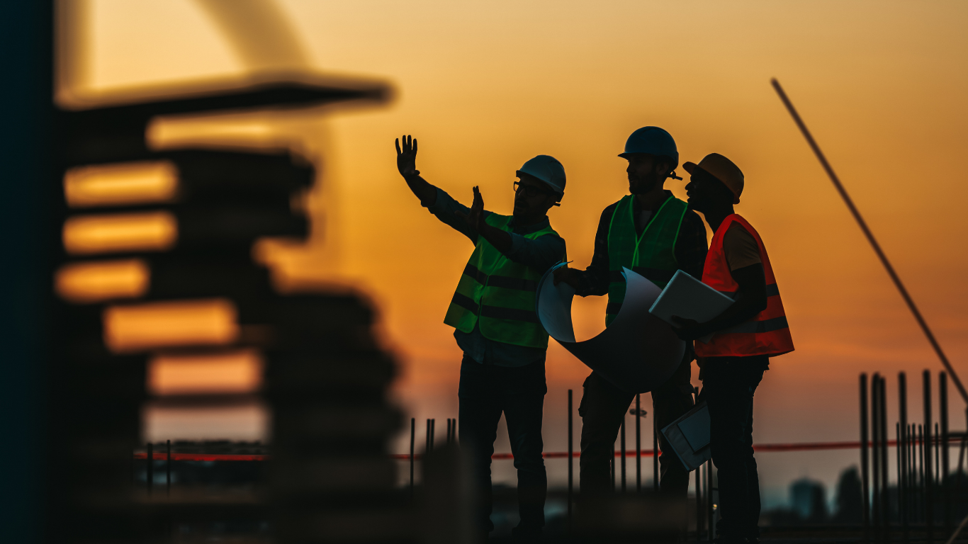 Workers installing plywood flooring on a wooden frame at a construction site