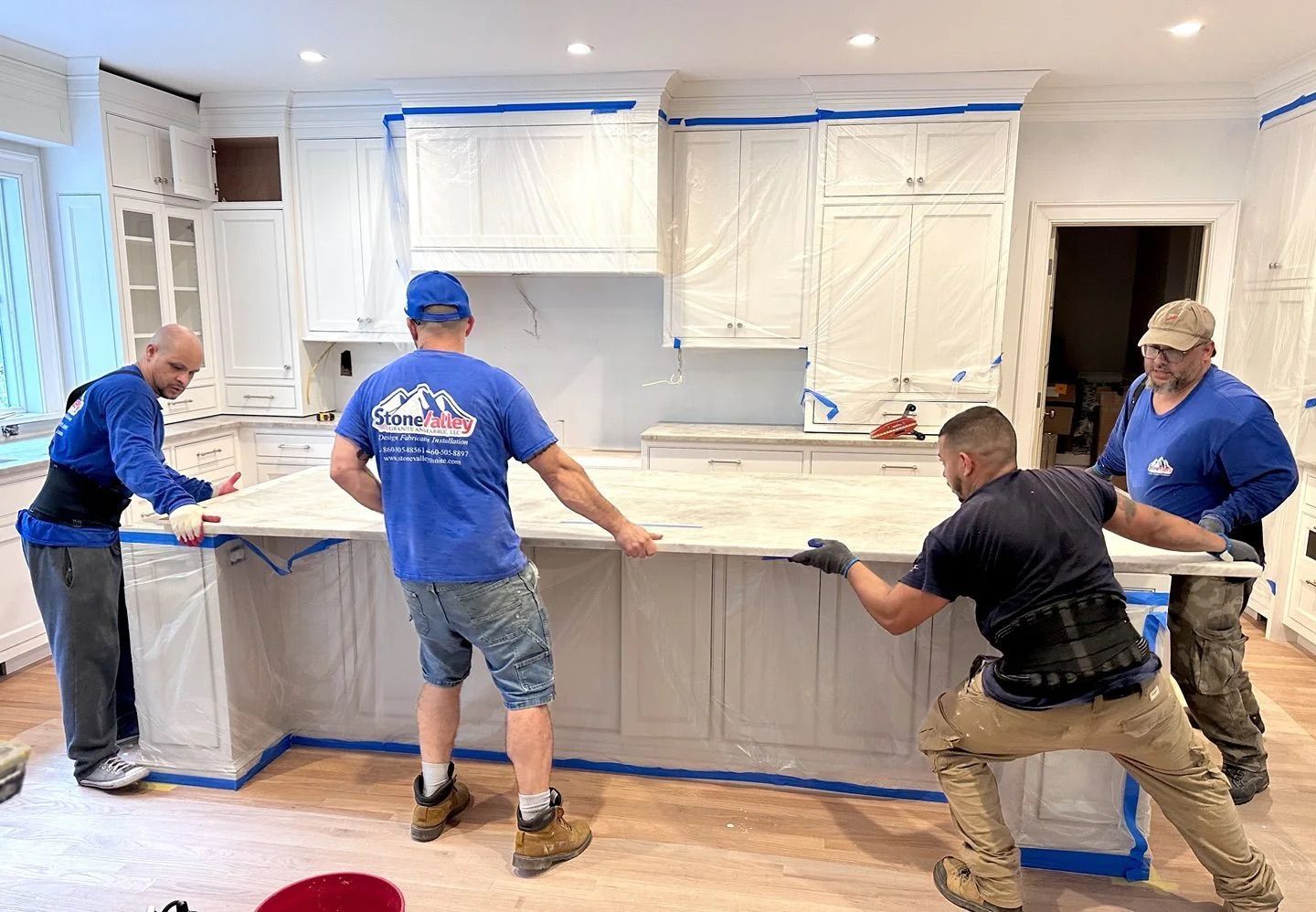 Two workers installing a white kitchen island countertop in a renovated room