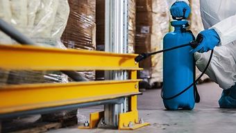 A person is spraying a warehouse with a sprayer.