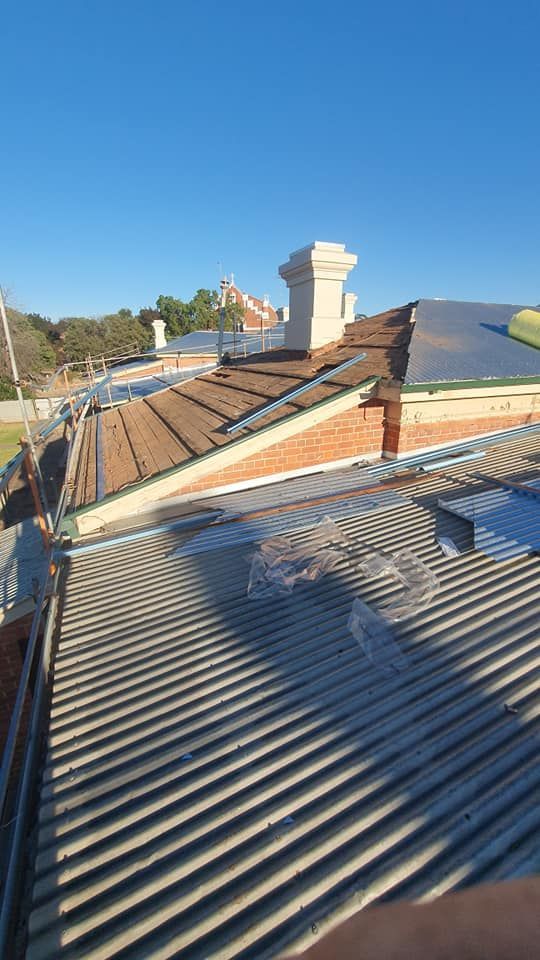 A rooftop view of a building with a chimney, featuring various roofing materials and a clear sky. — The Roofer Troopers (NSW) in Rutherglen, VIC