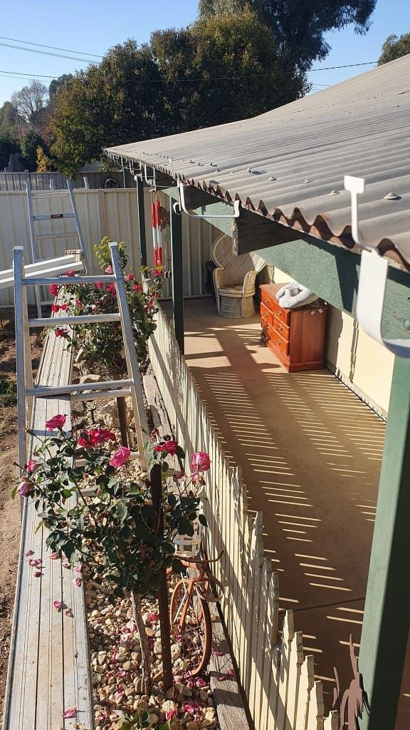 Side View of a Fenced Patio With Rose Bushes, Ladder, and a Small Wooden Cabinet — The Roofer Troopers (NSW) in Howlong, NSW
