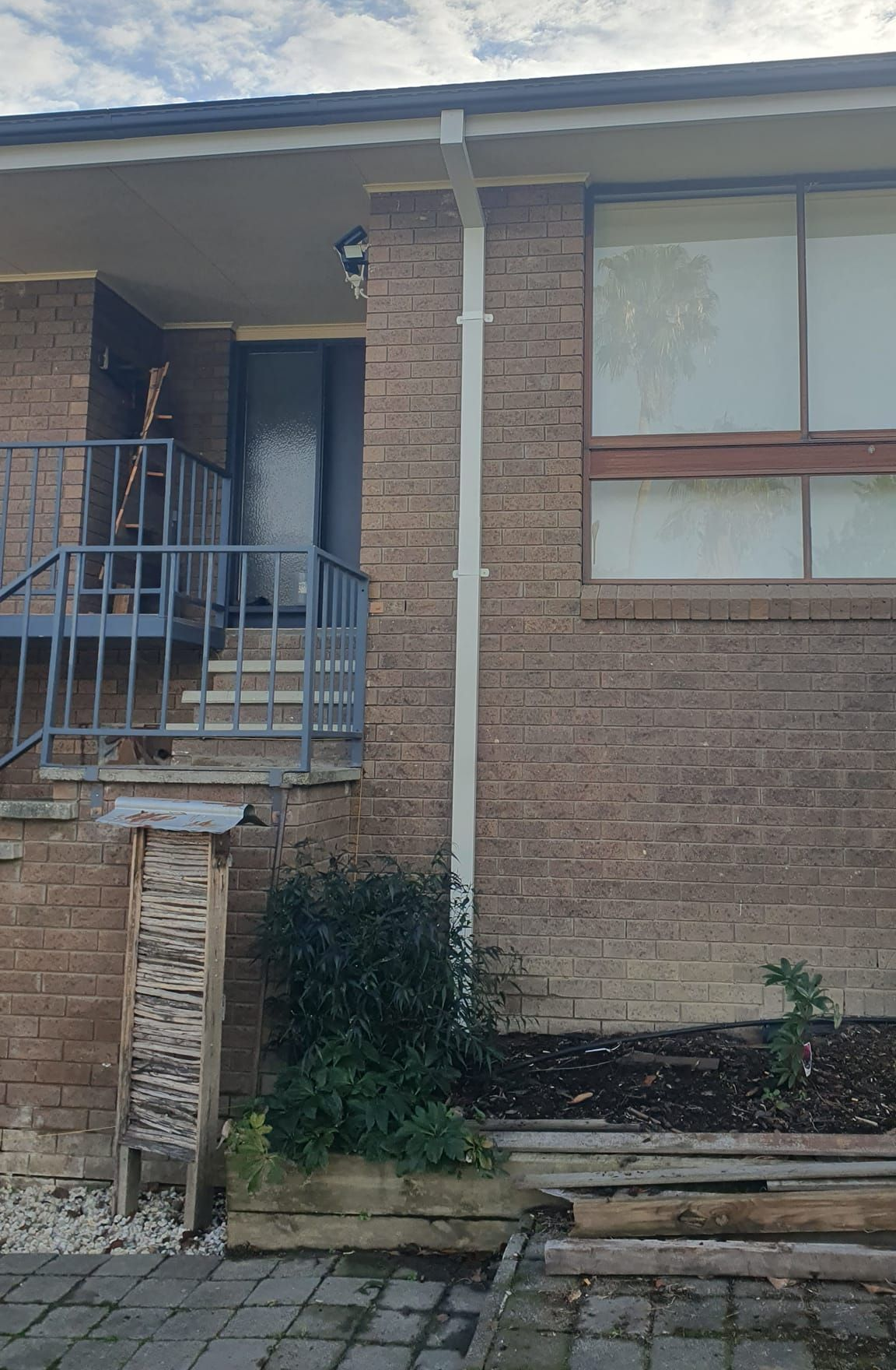 Brick building with steps to a doorway and a window, with a gutter and small shrub. — The Roofer Troopers (NSW) in Rutherglen, VIC