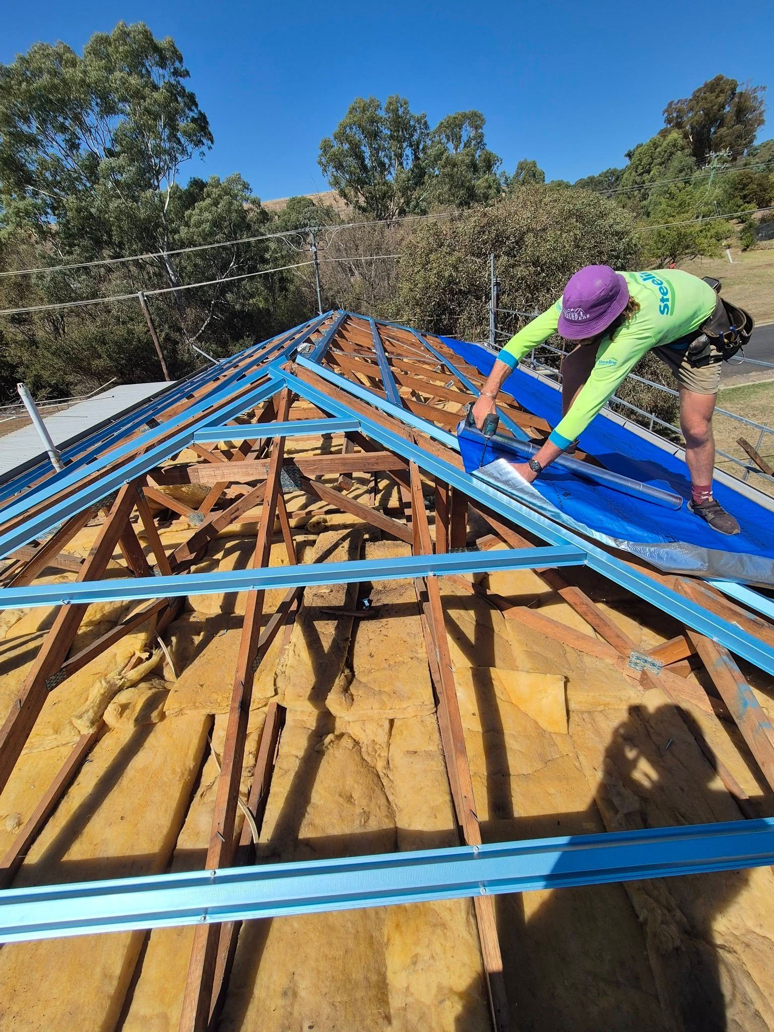 Worker Installing Blue Roofing Panels on a House Frame — The Roofer Troopers in Wodonga, VIC