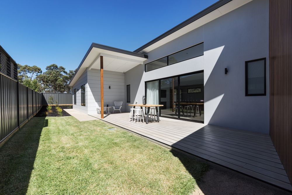 Backyard of a modern house with deck, grass, and fence on a sunny day. — The Roofer Troopers (NSW) in Howlong, NSW