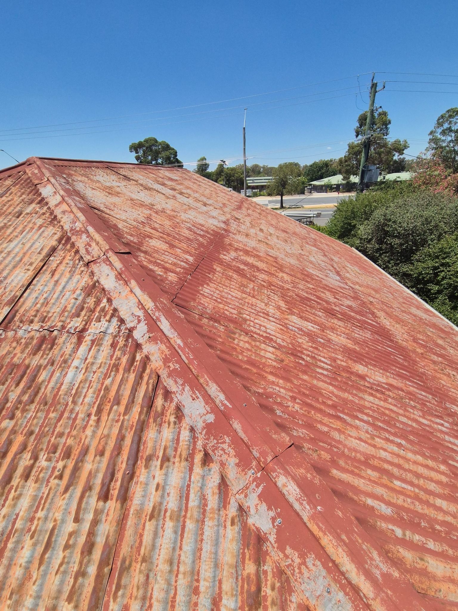 Rusty Corrugated Metal Roof Under a Clear Blue Sky — The Roofer Troopers in Wodonga, VIC