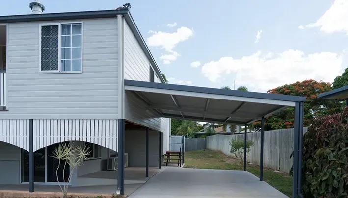 Two-story house with a carport. Light gray siding, black carport frame, concrete driveway. Cloudy sky. — The Roofer Troopers (NSW) in Howlong, NSW