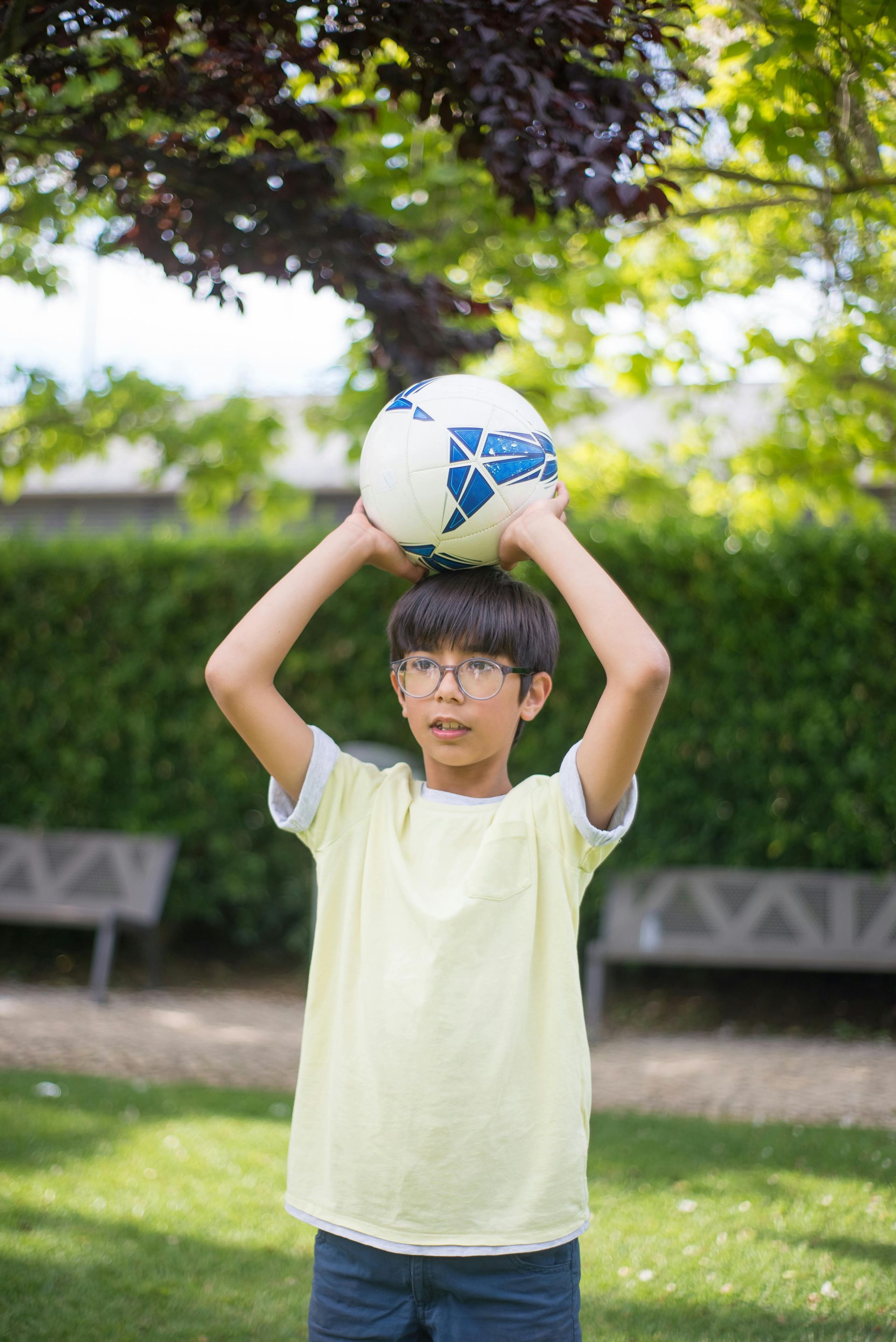 A young boy is holding a soccer ball over his head.