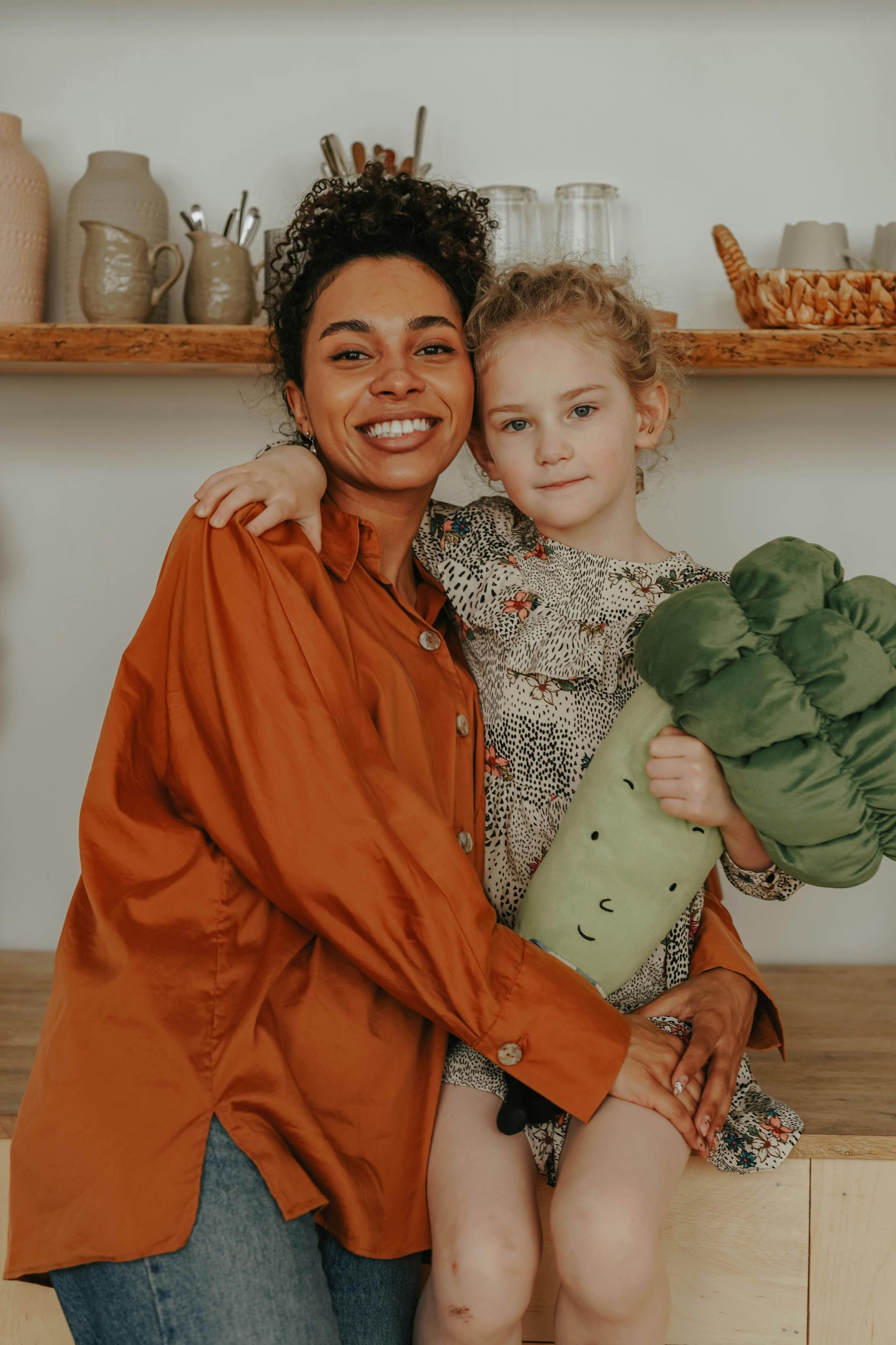 A woman is holding a little girl in her arms while sitting on a counter.