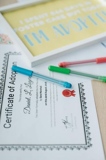 A certificate of adoption sits on a table next to pens