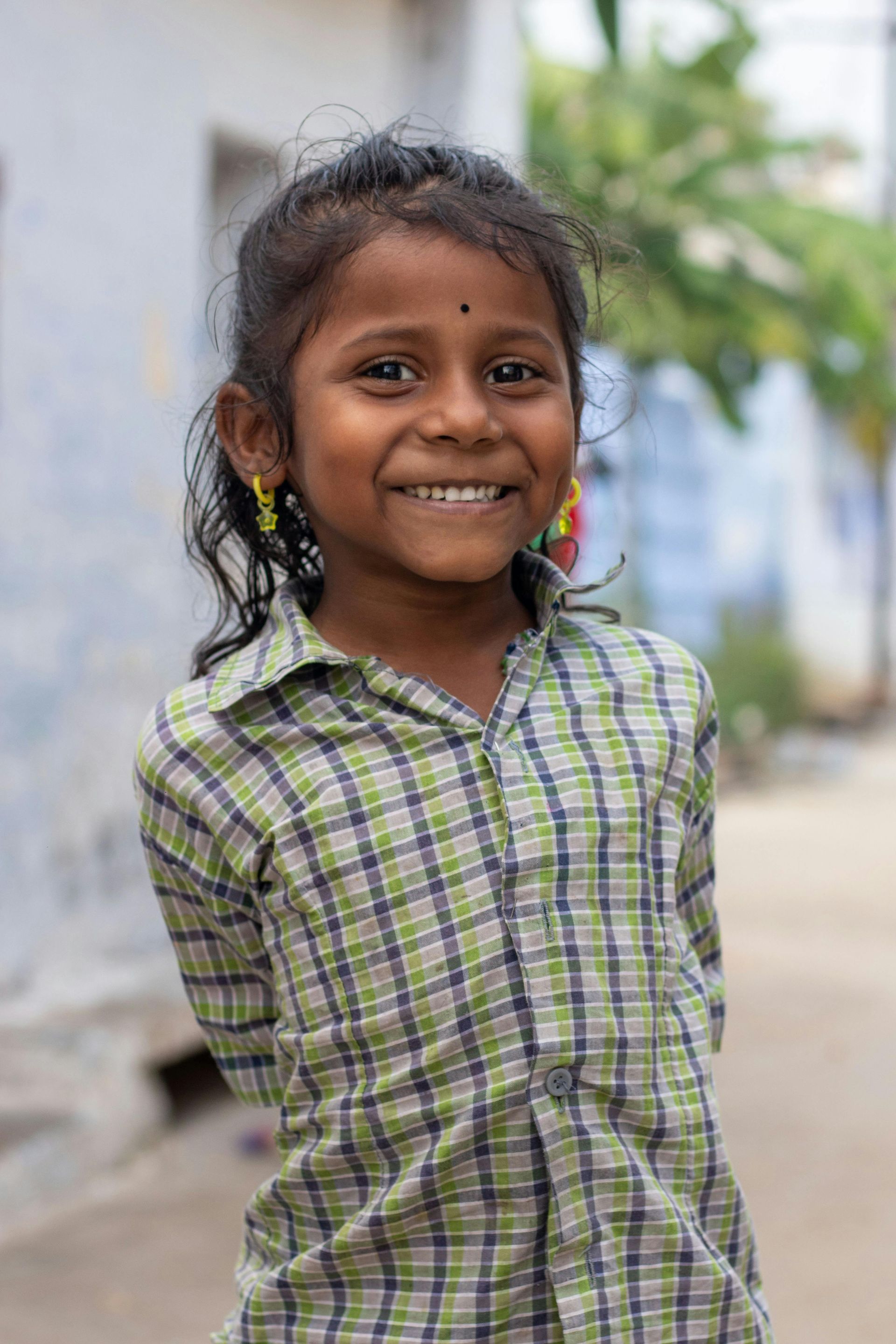 A little girl in a plaid shirt is smiling for the camera.