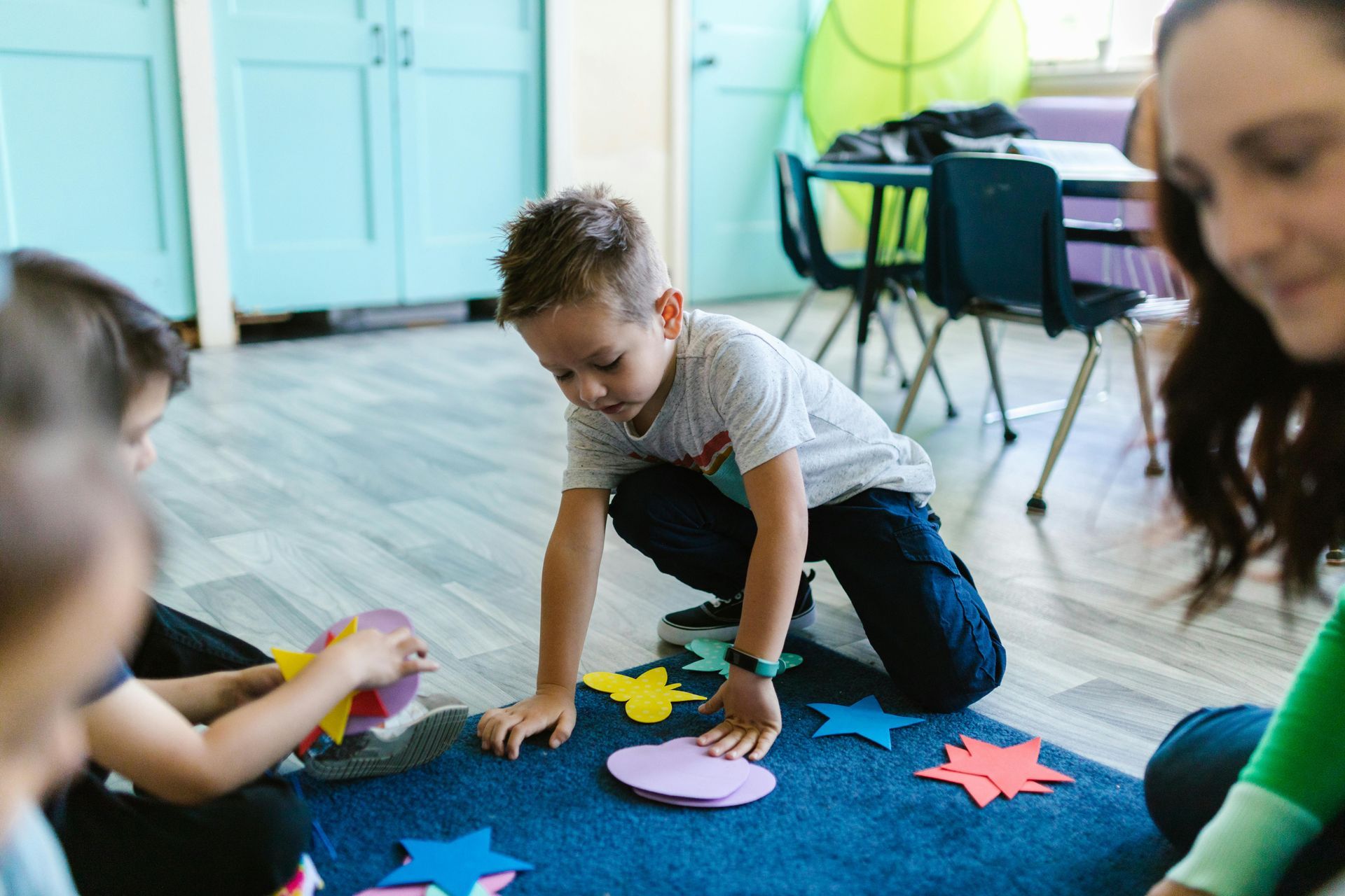 A group of children are playing with paper stars on the floor.