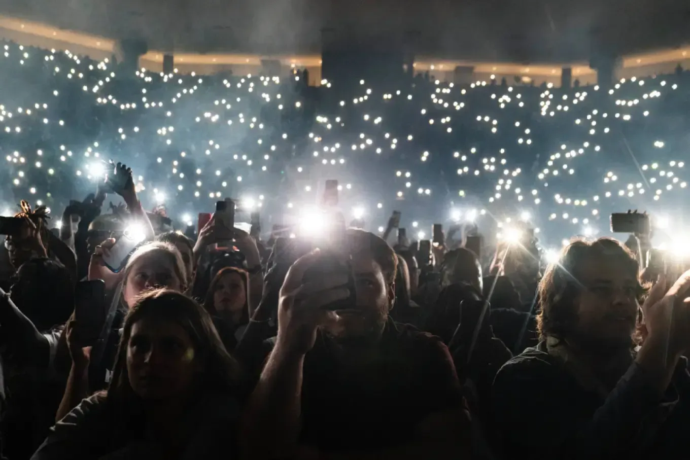 A crowd of people are taking pictures of a concert with their cell phones.