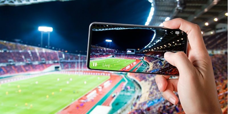 A person is taking a picture of a soccer stadium with a cell phone.