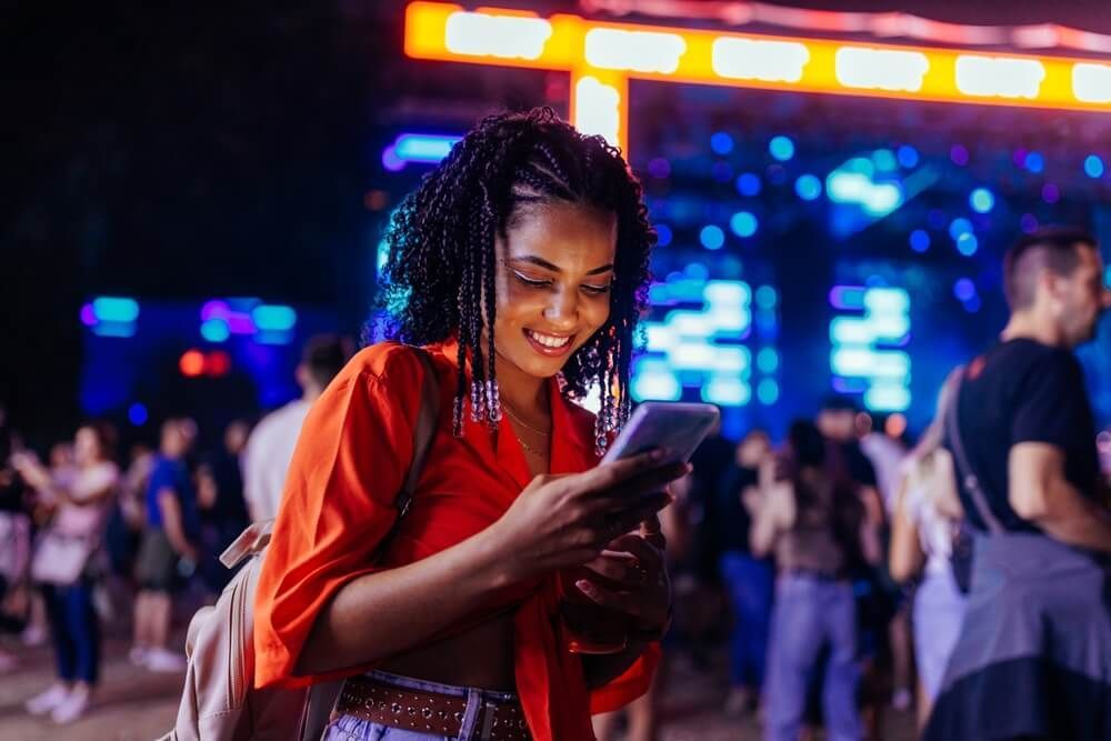 A woman is using a cell phone at a concert.