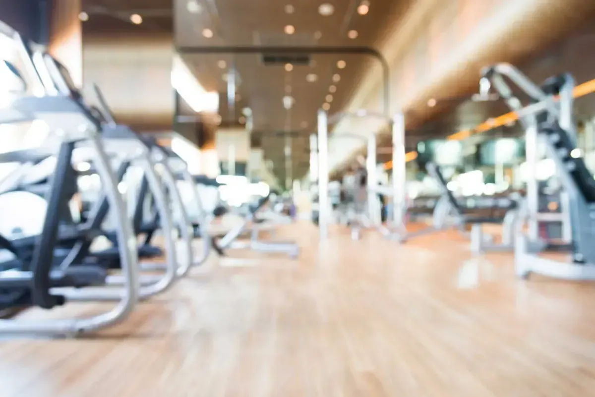 A blurred image of a gym with a lot of exercise equipment.