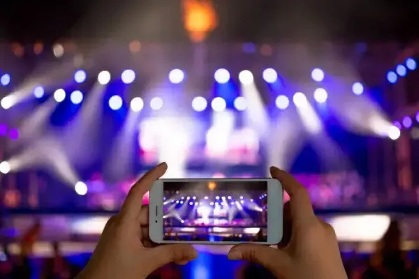 A person is taking a picture of a concert with a cell phone.