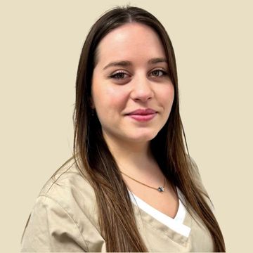 Frau in beigefarbener Kasack, lächelnd, in einem runden Rahmen vor neutralem Hintergrund.