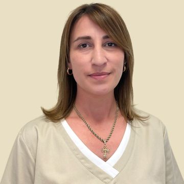 Frau in beigefarbener Kasack und Kette, lächelnd, in einem runden Rahmen vor neutralem Hintergrund.