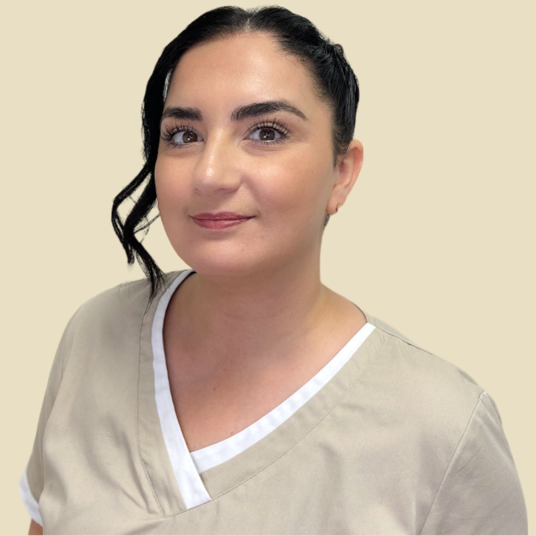 Foto Teammitglied Frau in beigefarbener Kasack, lächelnd, in einem runden Rahmen vor neutralem Hintergrund.