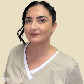 Frau in beigefarbener Kasack, lächelnd, in einem runden Rahmen vor neutralem Hintergrund.