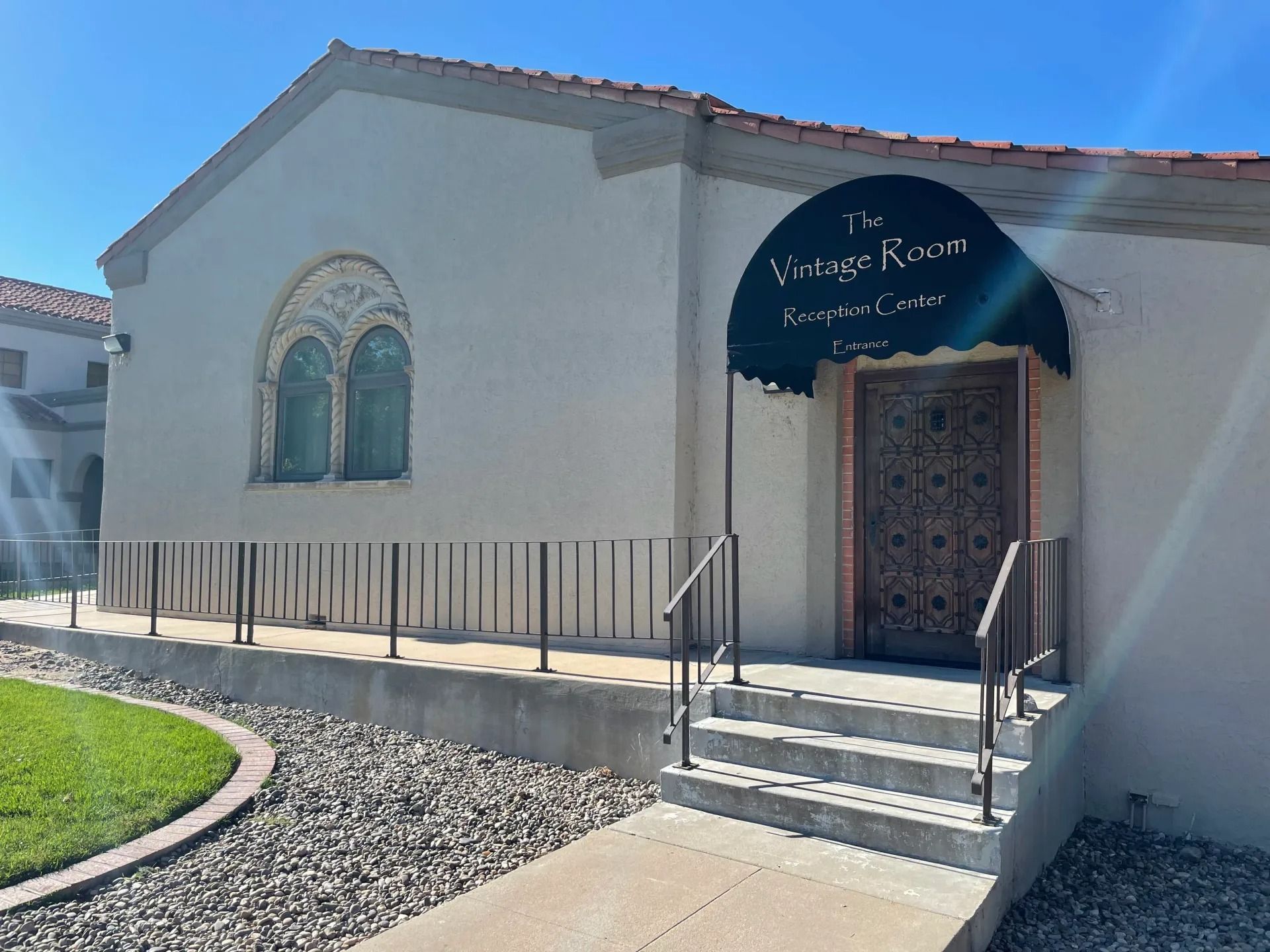 Aerial view of a green park with trees and roads. Cars are parked near the entrance.