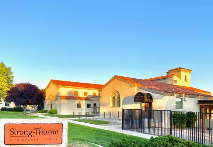 Rendering of a memorial with a central cross and surrounding structures, trees, and sky.