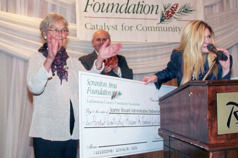 A woman is holding a large check for the foundation