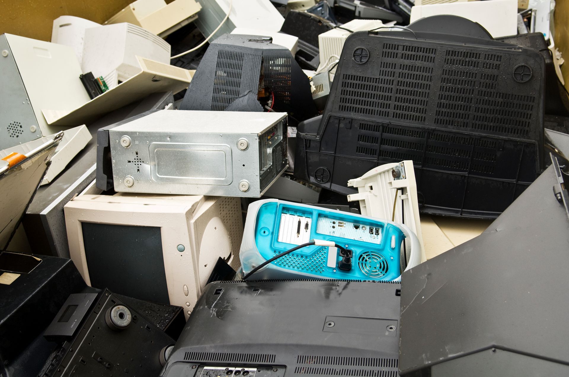 Pile of discarded electronic equipment, including computer monitors and a blue chassis.