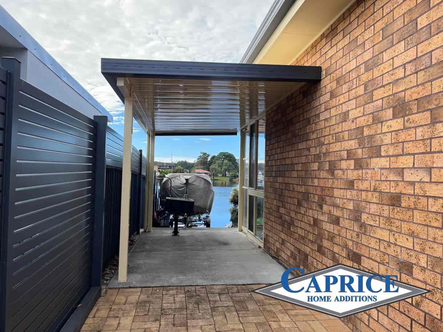 A Man Is Walking Under A Covered Driveway Next To A Garage — Caprice Home Additions In Port Macquarie, NSW