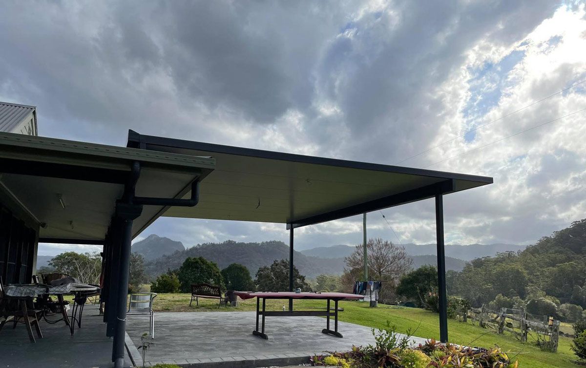 A Picnic Table Under a Covered Porch With Mountains in the Background — Caprice Home Additions In Taree, NSW