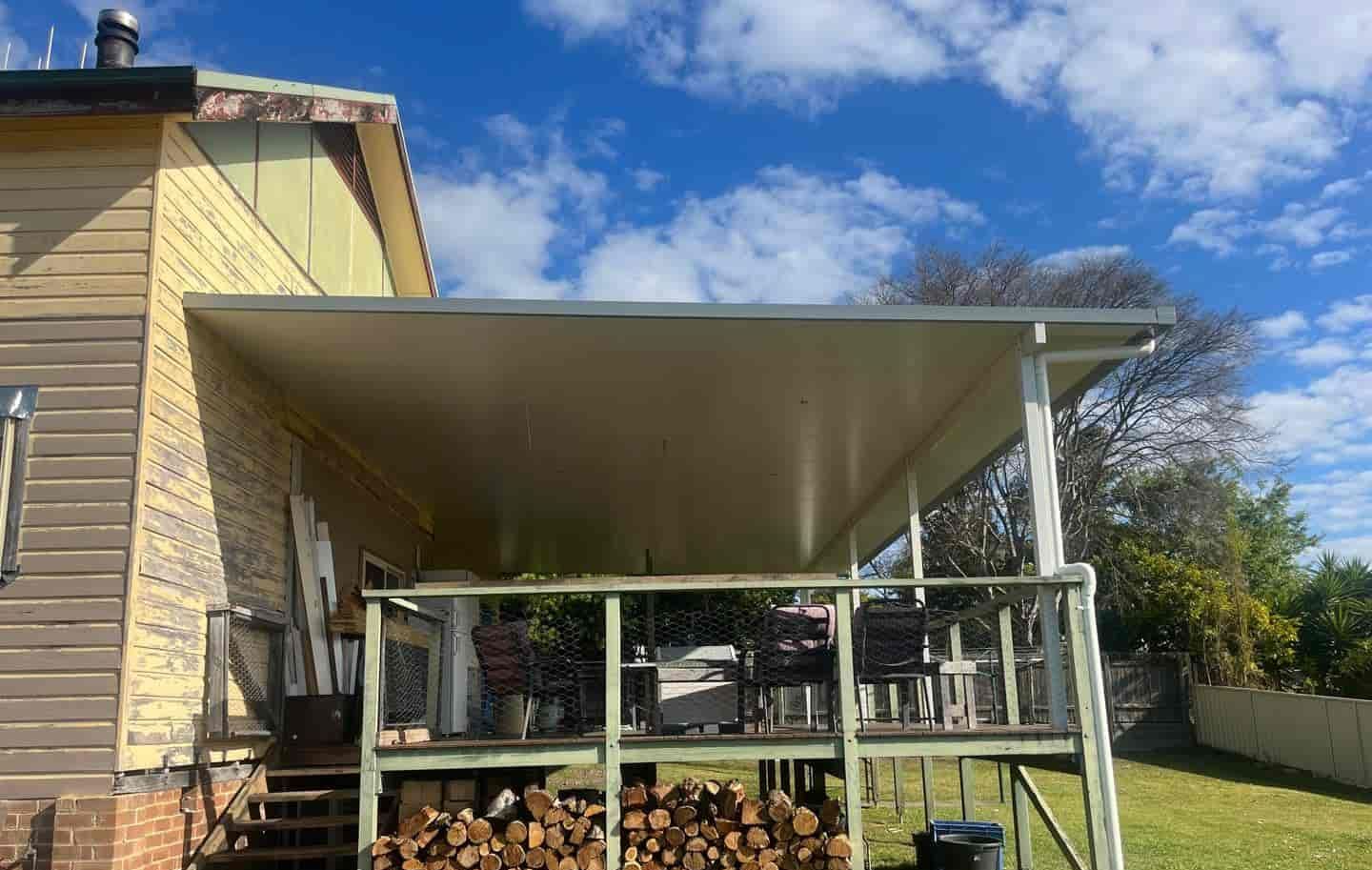 A House With A Covered Porch And A Pile Of Wood On The Ground — Caprice Home Additions In Old Bar, NSW