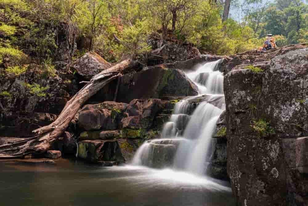 A Waterfall Is Surrounded By Rocks And Trees In The Middle Of A Forest — Caprice Home Additions In Gloucester, NSW