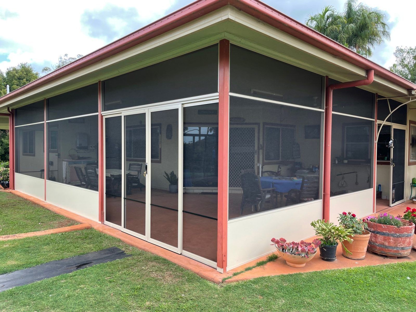 A Patio Area With Tables And Chairs Under A Canopy — Caprice Home Additions In Taree, NSW