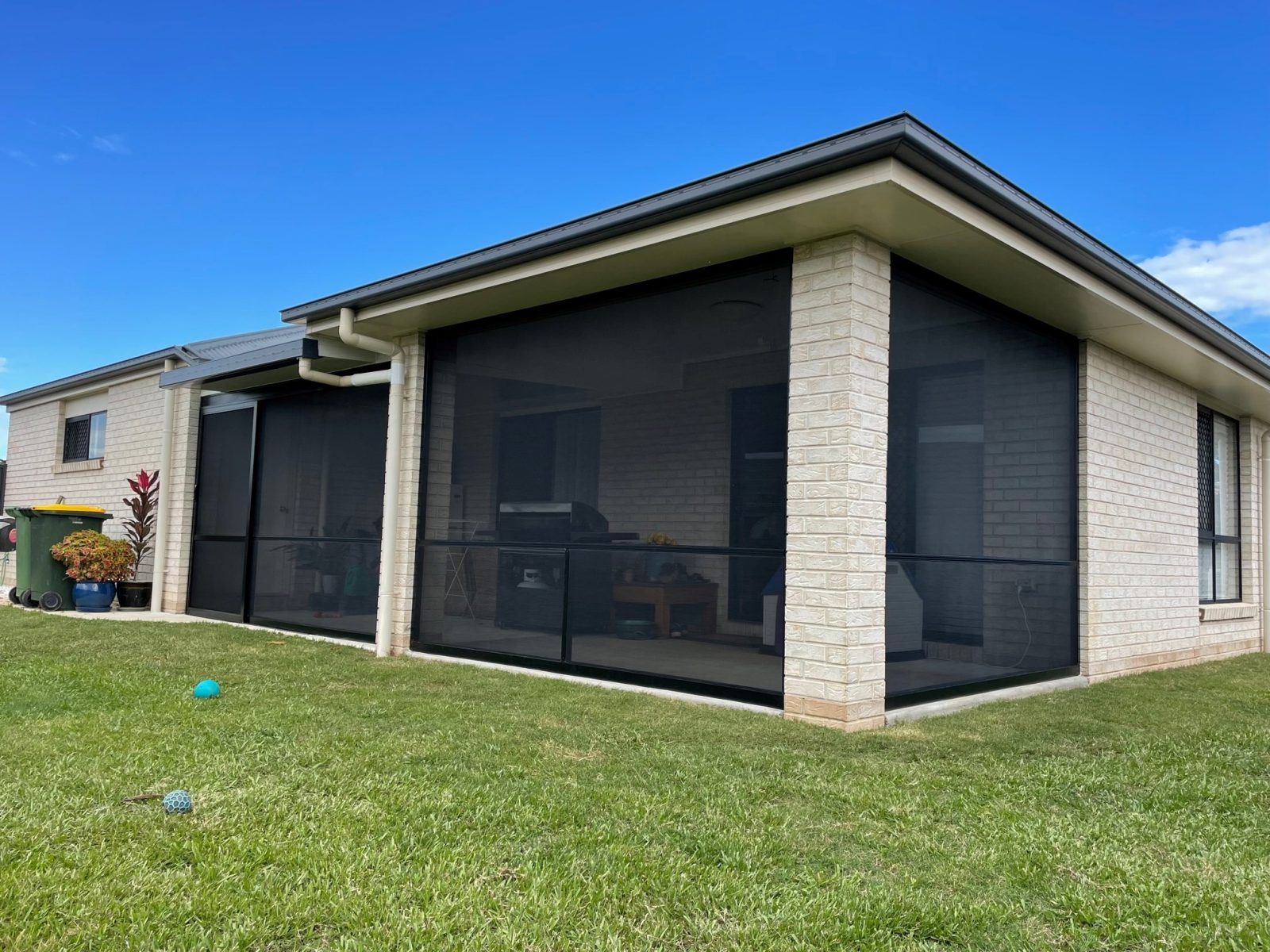 Brick House With Black Outdoor Blinds on a Sunny Day — Caprice Home Additions In Taree, NSW
