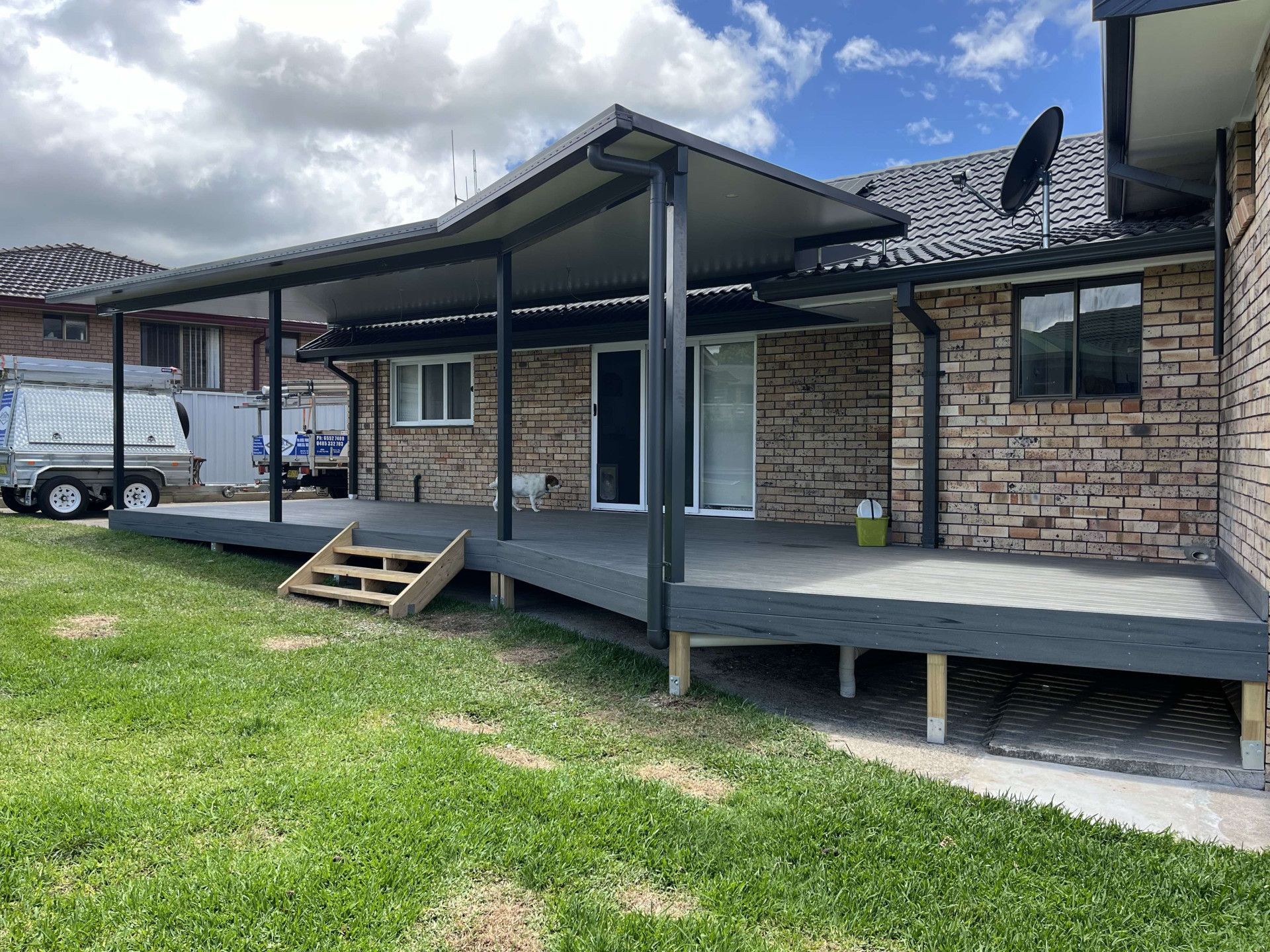 A Brick House With A Dog Walking Across The Porch — Caprice Home Additions In Taree, NSW